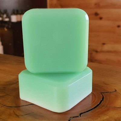 Dois sabonetes verdes claros quadrados numa superfície de madeira