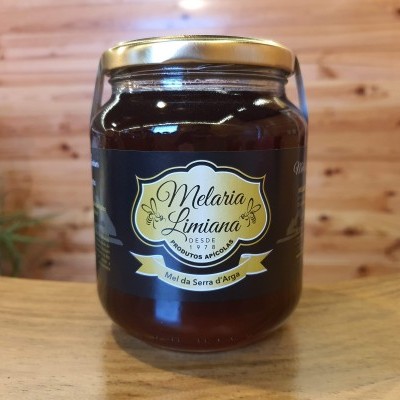 Frasco de mel Melaria Limiana com rótulo preto e amarelo sobre mesa de madeira