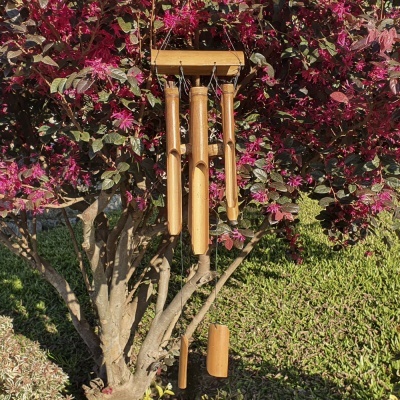 Sino dos ventos em bambu pendurado numa árvore com folhas vermelhas