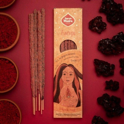 Incensos Sagrada Madre Fuerza com embalagem e bastões sobre fundo vermelho com especiarias.