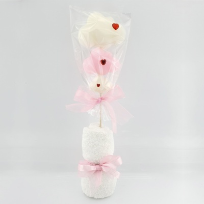 Toalhas brancas decoradas com laços rosa e corações vermelhos em peça decorativa embrulhada