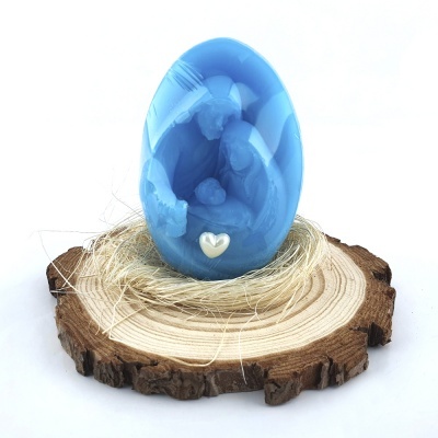 Estatueta azul em forma de ovo com figura maternal em relevo sobre base de madeira