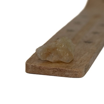 Pedra translúcida bege sobre régua de madeira clara