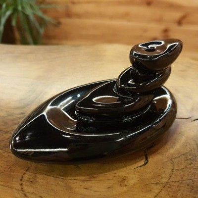 Escultura preta em forma orgânica em cima de madeira rustica