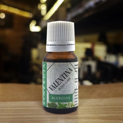 Frasco âmbar com rótulo de óleo essencial para alergias sobre mesa de madeira