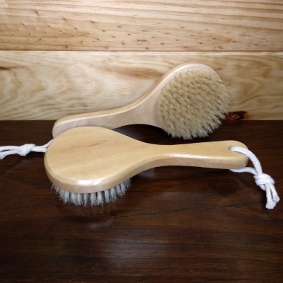 Dois pincéis de madeira com cerdas naturais e cordões brancos sobre superfície escura