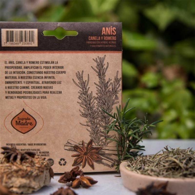 Embalagem de papel kraft com texto e ilustração de anis e alecrim ao lado de ramos frescos e especiarias sobre superfície de madeira