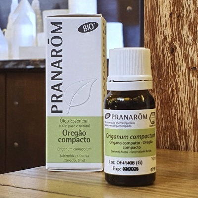 Frasco de óleo essencial de Orégano compacto Pranarôm com embalagem na mesa de madeira