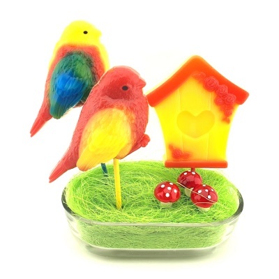 Decoração colorida com pássaros, casinha e cogumelos numa base transparente com fibra verde