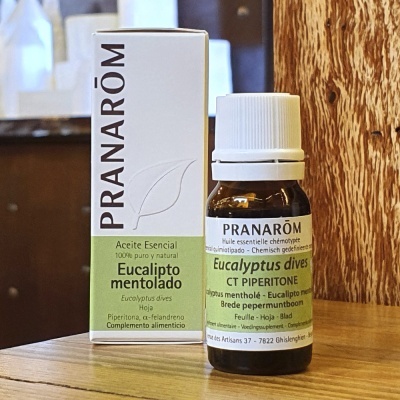 Frasco de óleo essencial de eucalipto mentolado Pranarôm com caixa branca ao lado sobre mesa de madeira