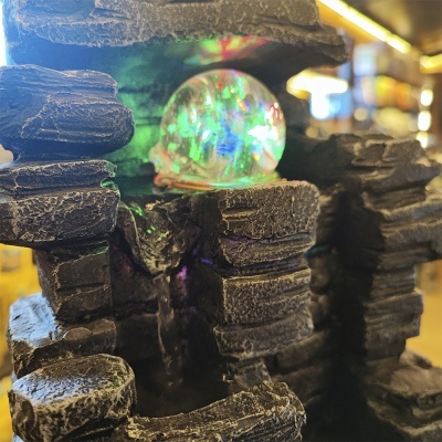 Fonte decorativa de pedra com esfera luminosa e luzes coloridas