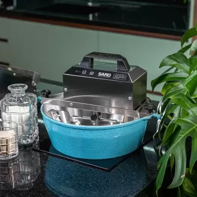 Máquina misturadora SARO em aço inoxidável com base azul turquesa numa cozinha