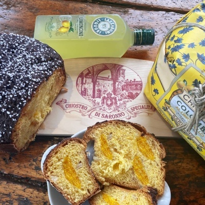 Bolo fatiado com açúcar granulado, garrafa de limoncello, embalagem amarela e tábua de madeira gravada numa mesa de madeira