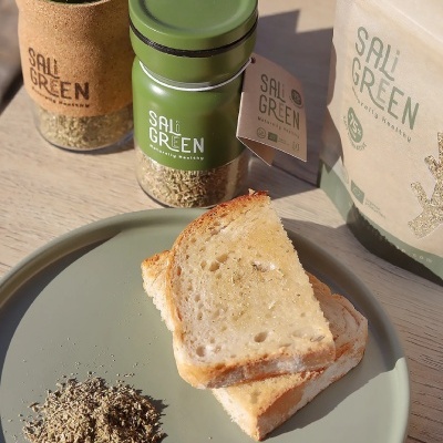 Fatias de pão e ervas secas em prato verde com frascos e saco SALi GREEN