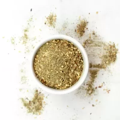 Mistura de especiarias em pó num recipiente branco com especiarias espalhadas à volta