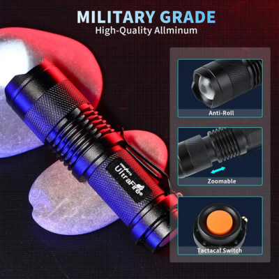 Lanterna portátil preta de alumínio com botão laranja e clips de fixação sobre pedras