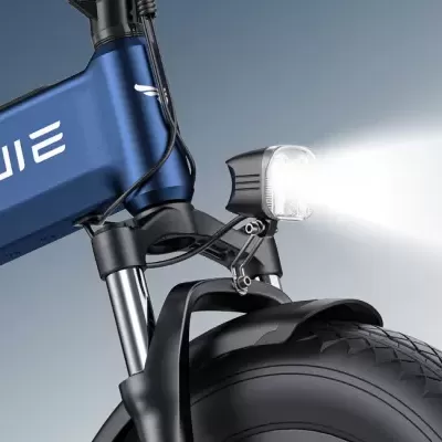 Bicicleta elétrica azul com farol dianteiro aceso e pneus largos pretos
