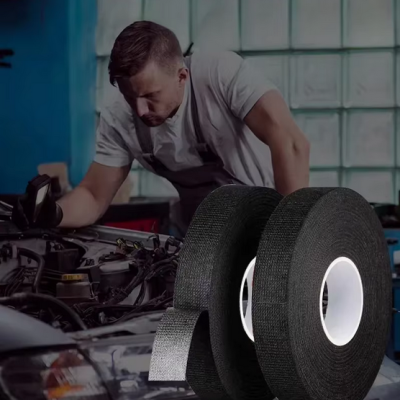 Rolos de fita isolante preta com núcleo branco em frente a homem a trabalhar num motor de carro