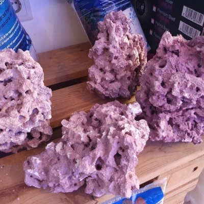 Pedras corais artificiais roxas claras com textura porosa sobre madeira clara