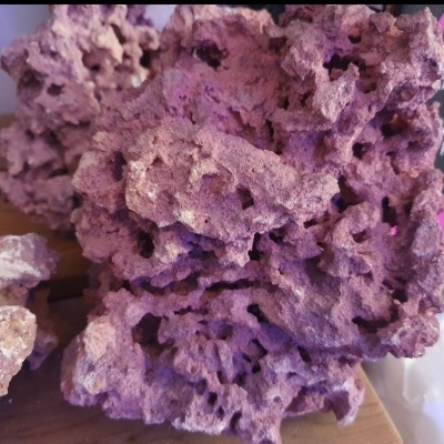 Rocha vulcânica castanha porosa sobre madeira com embalagem ao fundo