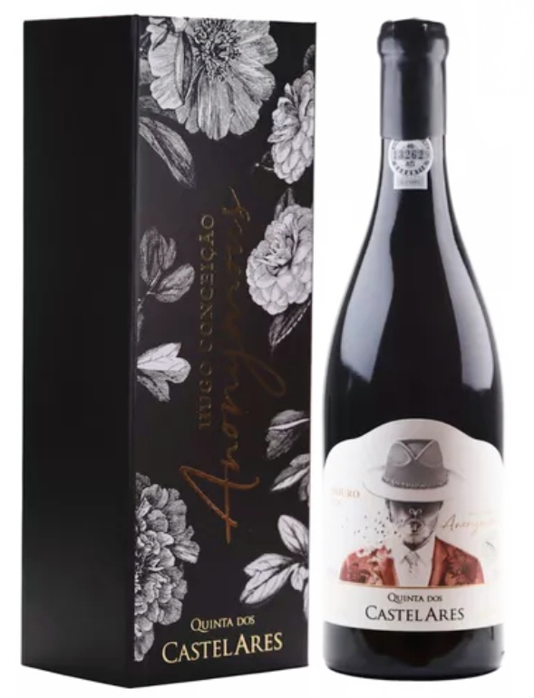 Garrafa de vinho tinto ao lado de caixa preta com ilustrações de flores.