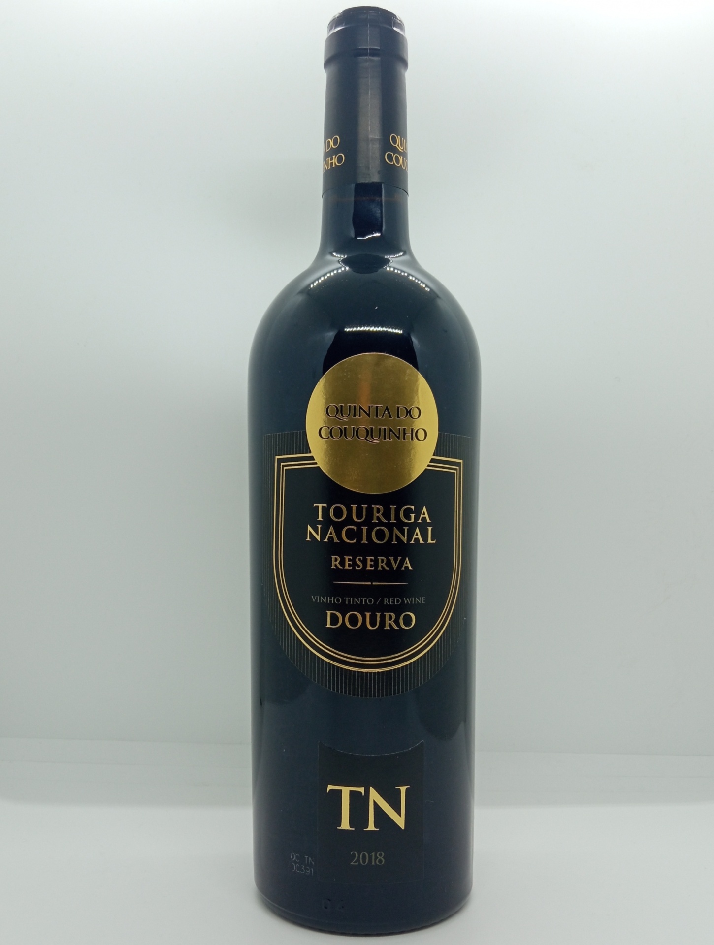 Garrafa de vinho tinto com rótulo preto e dourado da Quinta do Caminho