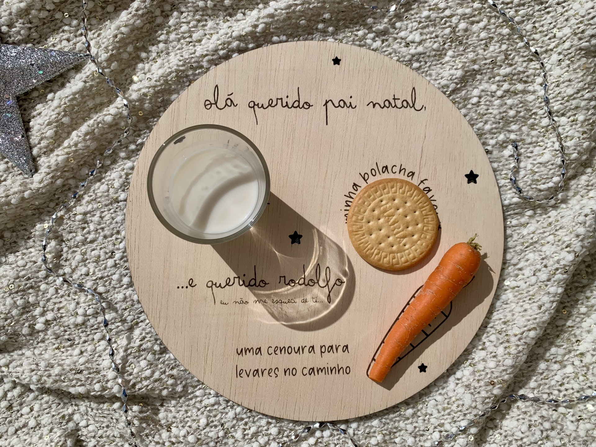 Prato redondo de madeira com leite, bolacha e cenoura sobre tapete cinza