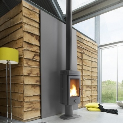 Lareira a lenha preta junto a parede de madeira decorativa e candeeiro amarelo em sala moderna com janela grande