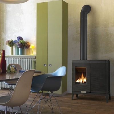 Sala de jantar com mesa, cadeiras coloridas, armário verde e aquecedor a lenha