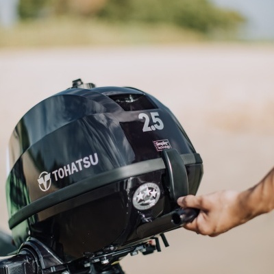 Motor de popa preto Tohatsu 2.5 com mão segurando puxador de arranque