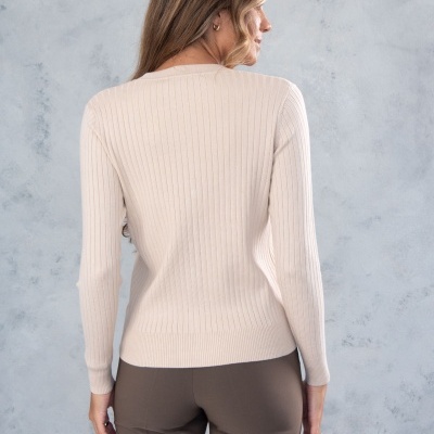 Camisola bege de malha de riscas verticais, vista de costas, com calças castanho escuras