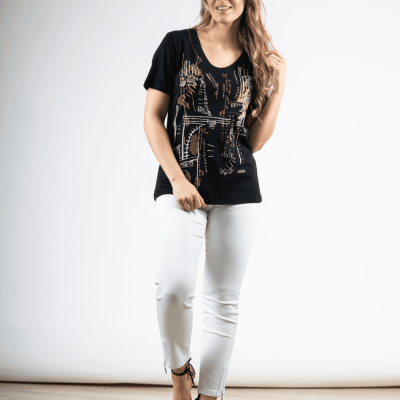Mulher com blusa preta estampada, calças brancas e sandálias pretas em fundo branco