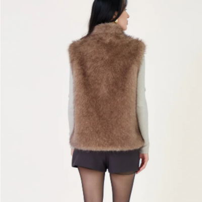 Mulher vista de costas com colete castanho de pelo e roupa preta e branca