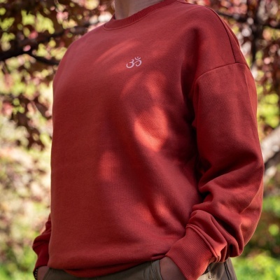 Sweatshirt terracota com símbolo OM branco no peito, usada ao ar livre