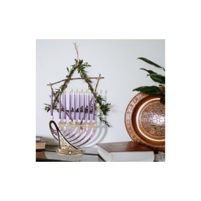 Castiçal de Hanukkah com velas lilás pendurado na parede com decoração verde e objetos ao redor