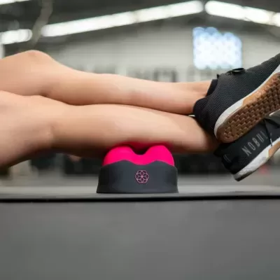 Produto de fitness rosa e preto para massagem muscular sob pernas com ténis pretos