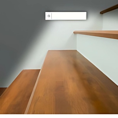 Escada interior com degraus em madeira castanha e parede branca com placa retangular