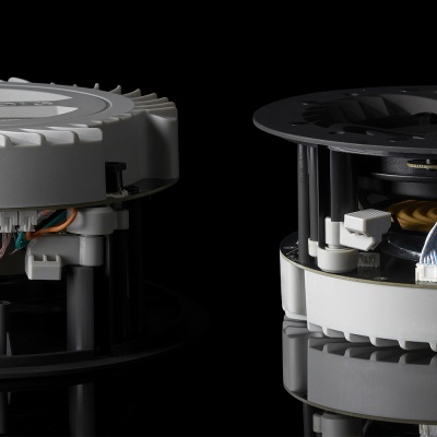 Dois dispositivos eletrônicos circulares com componentes visíveis e fios coloridos sobre superfície reflexiva preta