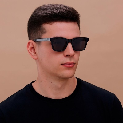 Homem com óculos de sol pretos contra fundo bege
