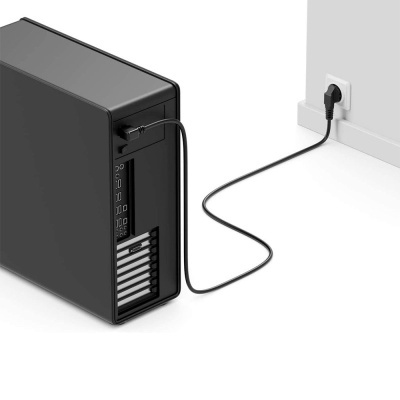 Computador de secretária preto ligado a tomada com cabo elétrico