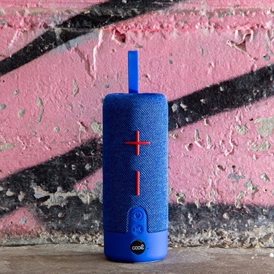 Coluna portátil azul com botões vermelhos em parede rosa com grafitis