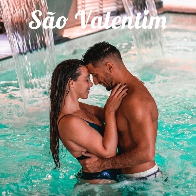 Casal na piscina abraçado com cascata de água ao fundo e texto São Valentim