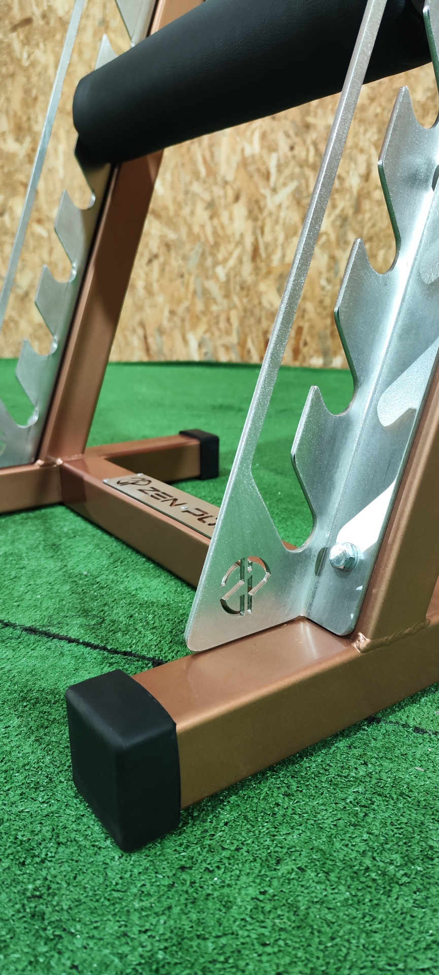 Suporte metálico para halteres castanho com apoios prateados em tapete verde