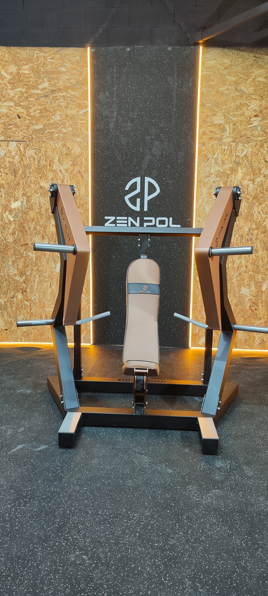 Máquina de levantamento de pesos com almofada bege e estrutura metálica cinza, com logotipo ZENPOL.