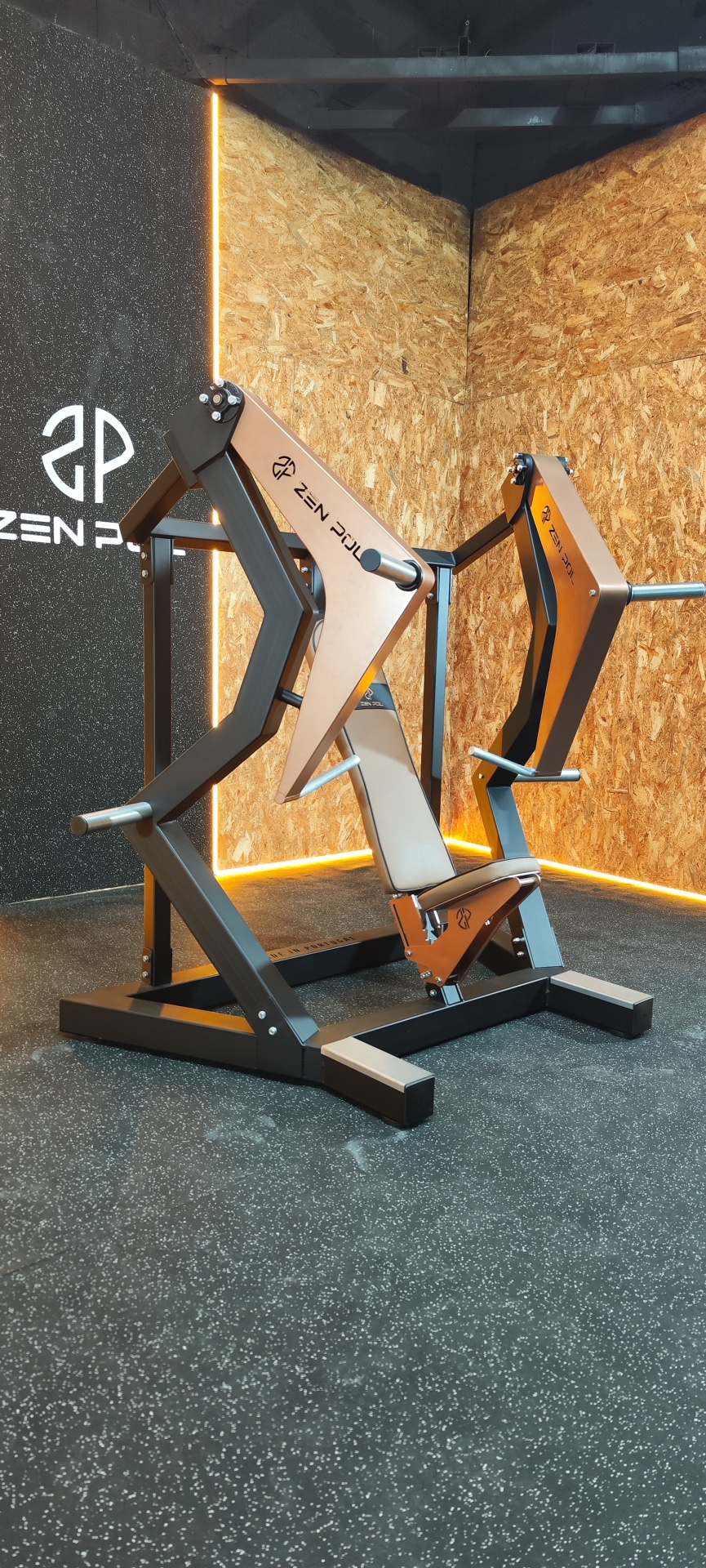 Máquina de treino de peso de musculação com estrutura metálica preta e detalhes metálicos em bronze num ginásio