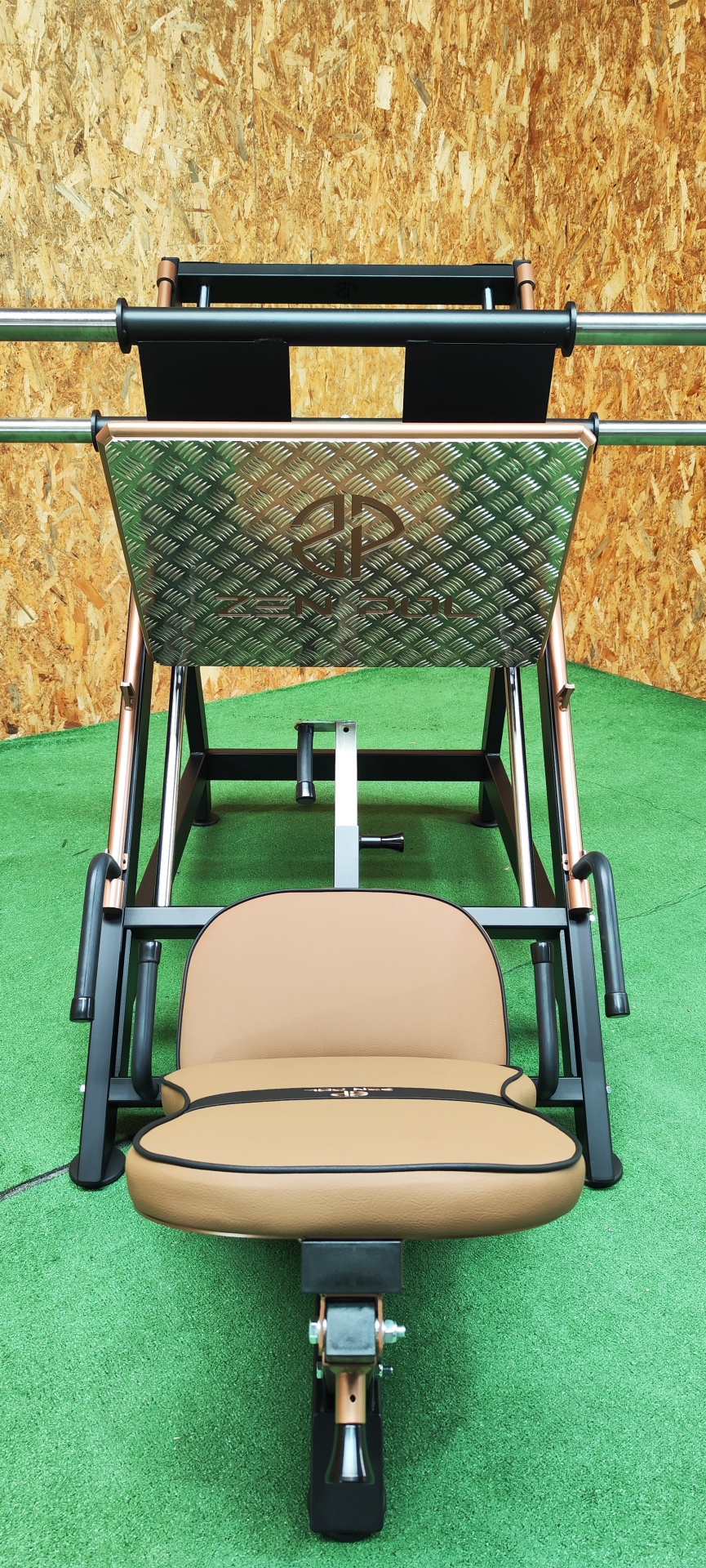 Máquina de exercício para pernas com assento bege e painel metálico em piso verde