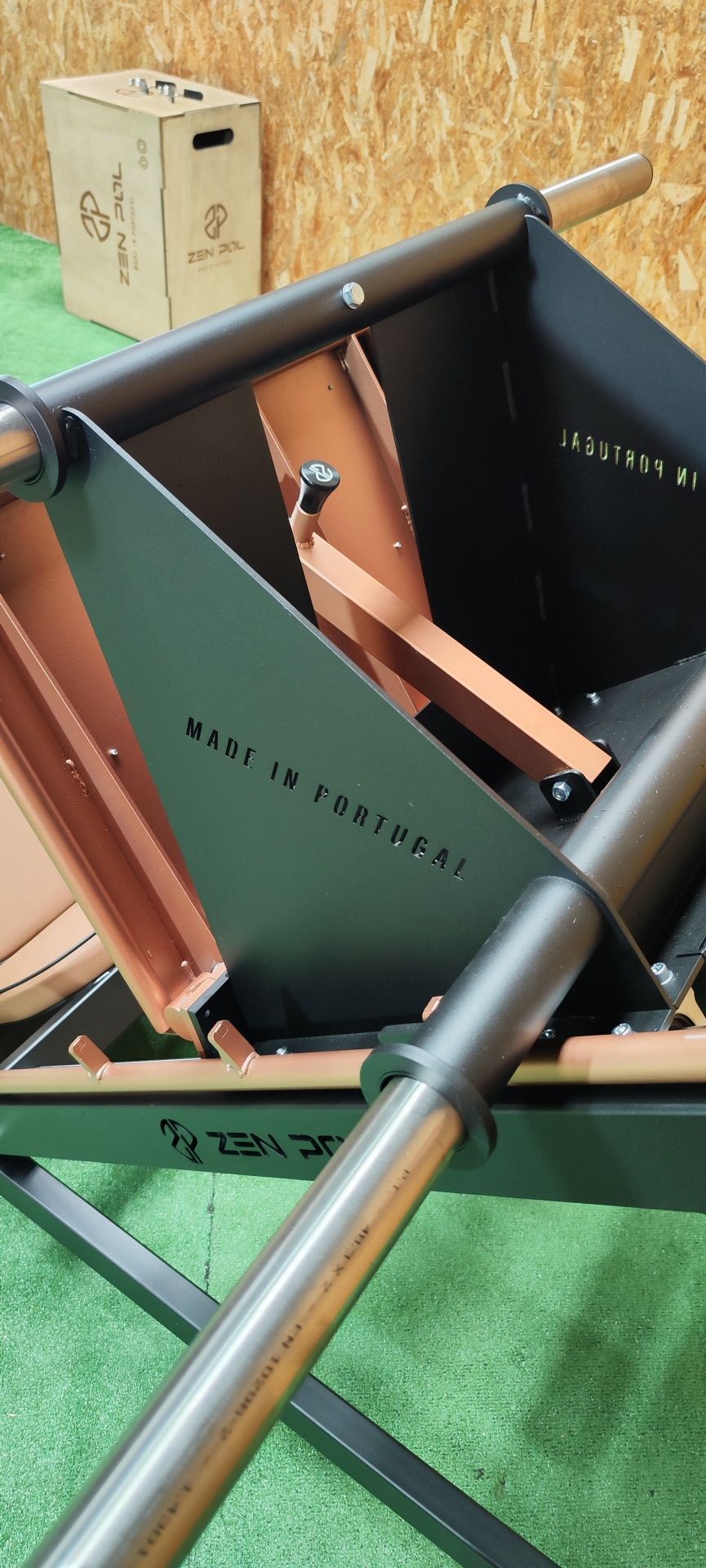 Carrinho de mão metálico preto e castanho com texto MADE IN PORTUGAL e logo ZEN SOIL em fundo de madeira e chão verde