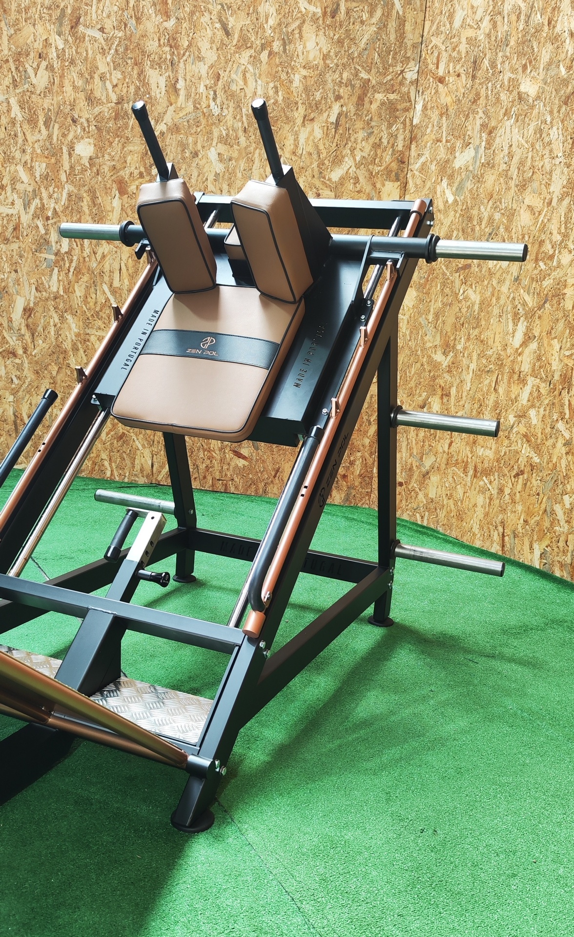 Máquina de musculação com almofadas castanhas e pretas em ambiente de ginásio