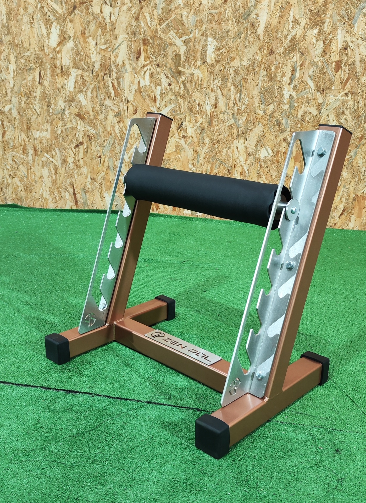 Suporte metálico dourado e prateado para barra de exercício com espuma preta em relva sintética