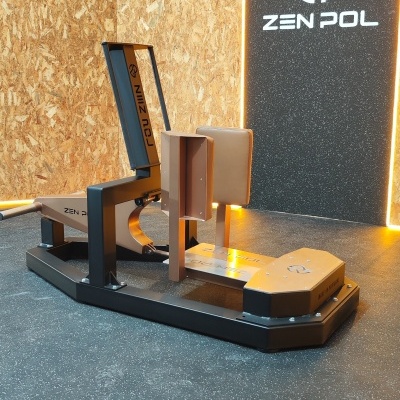 Máquina de ginásio bege e preta com logo ZEN POL num espaço com paredes de madeira OSB e parede preta.